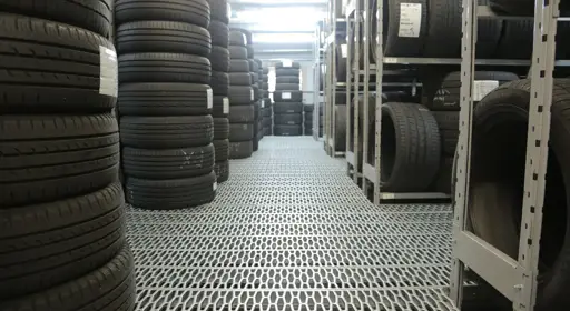 Was gilt es bei der richtigen Lagerung von Reifen zu beachten?  In einer Halle lagern Reifen in Regalen.