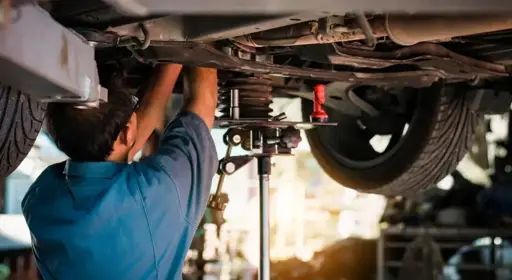 Wann muss ich meine Stoßdämpfer wechseln? Ein Kfz-Mechaniker nimmt einen Wechsel der Stoßdämpfer am Auto vor.