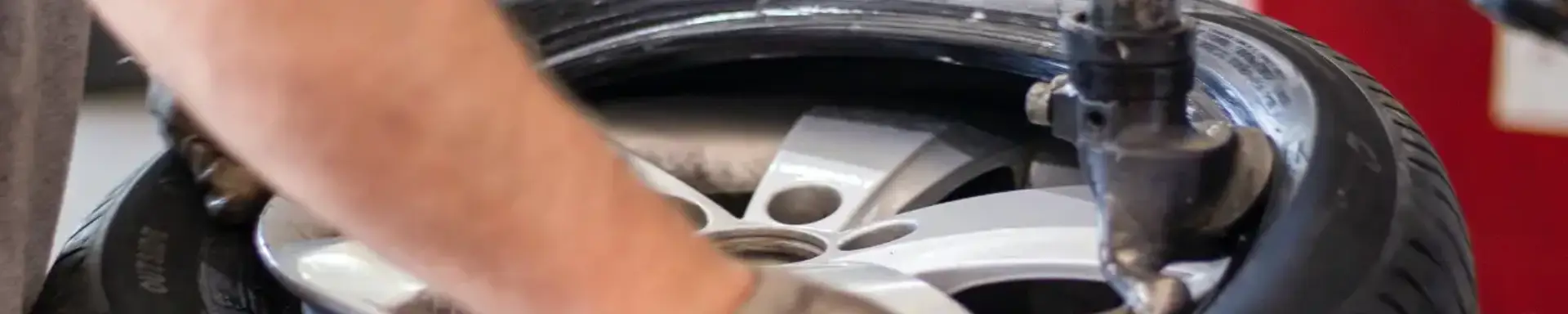 Mit welchen Kosten muss ich beim Reifen aufziehen und wuchten rechnen? Ein Werkstattmitarbeiter ist damit beschäftigt, Reifen aufzuziehen, die gesamten Kosten dafür hat er bereits vorkalkuliert.