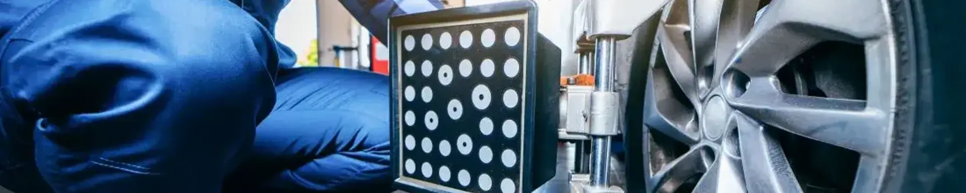 Wann ist die Achsvermessung notwendig?  Ein Werkstattmitarbeiter platziert ein Gerät zur Achsvermessung am Fahrzeug.