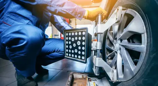 Wann ist die Achsvermessung notwendig?  Ein Werkstattmitarbeiter platziert ein Gerät zur Achsvermessung am Fahrzeug.