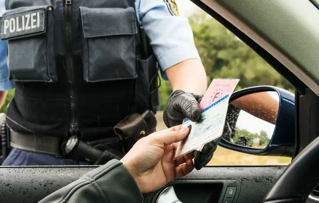 Die Grafik zeigt eine Verkehrskontrolle, bei der dem Fahrer ein Bußgeld bezahlen muss, weil seine Reifen zu alt sind, worauf die DOT-Nummer hinweist.
