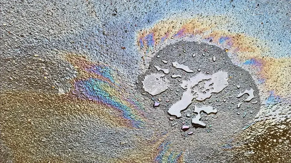 Welche Strafen drohen, wenn man Altöl illegal entsorgt? Eine Ölspur auf der Straße, die symbolisiert, wie gefährlich das illegale Entsorgen von Altöl für die Umwelt ist.