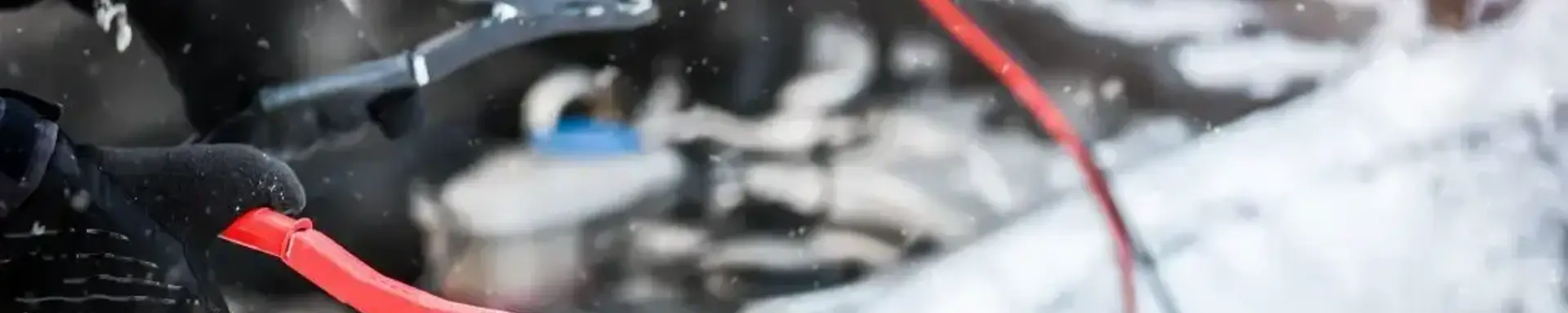 Wie kann ich mein Auto richtig überbrücken? Eine behandschuhte Hand hält ein Überbrückungskabel.