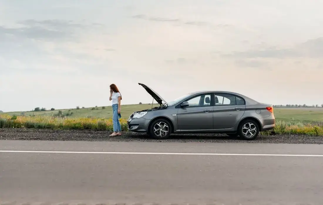 Die Grafik zeigt ein Auto mit geöffneter Motorhaube und die Fahrerin am Straßenrand.