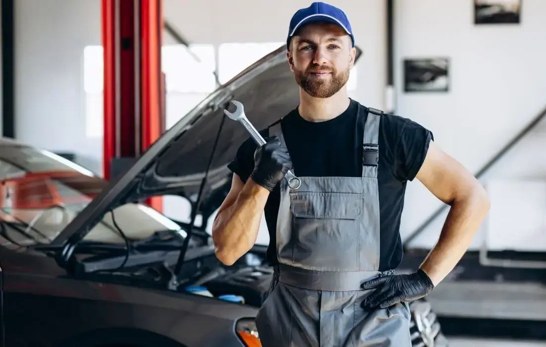 Ein Mann in einer Werkstatt benutzt beim Wechseln der Autobatterie das richtige Werkzeug.