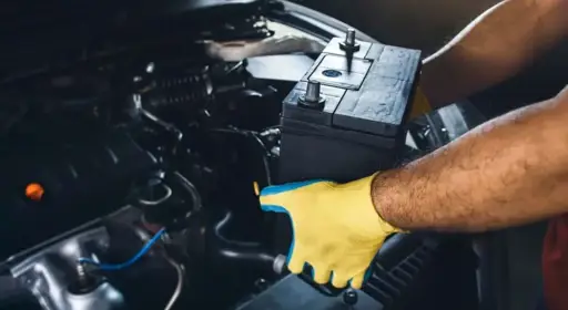 Was ist beim Wechseln der Autobatterie zu beachten?  Die Grafik zeigt eine Person beim Einbauen der Autobatterie, um sie zu wechseln.