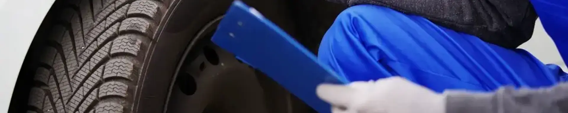 Wann lohnt es sich die Autoreifen zu wechseln?   Ein Werkstattmitarbeiter prüft die Profiltiefe, um einzuschätzen, wann die Reifen gewechselt werden müssen.