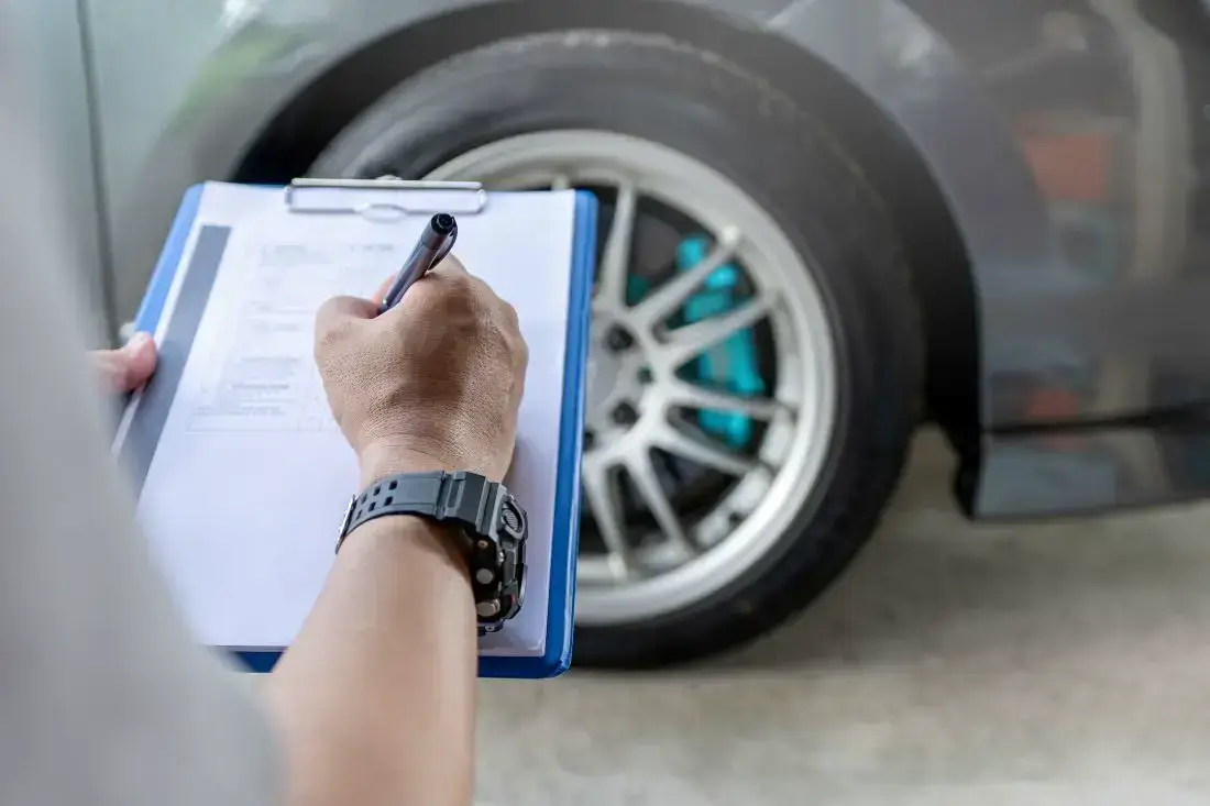 Ein TÜV-Prüfer schreibt im Protokoll, wann man die Reifen das nächste Mal wechseln sollte.