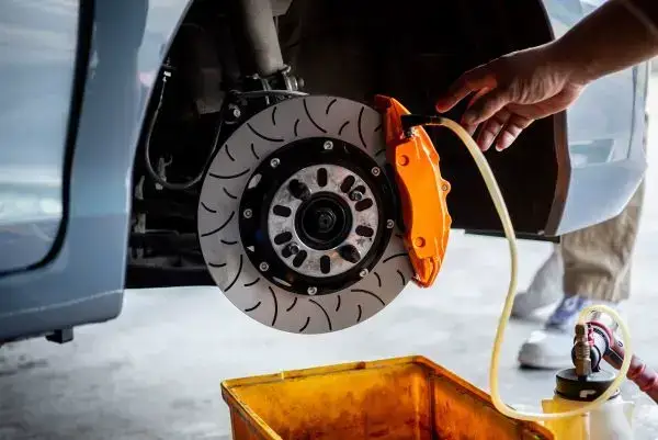 Die Bremsen am PKW werden in der Werkstatt entlüftet.