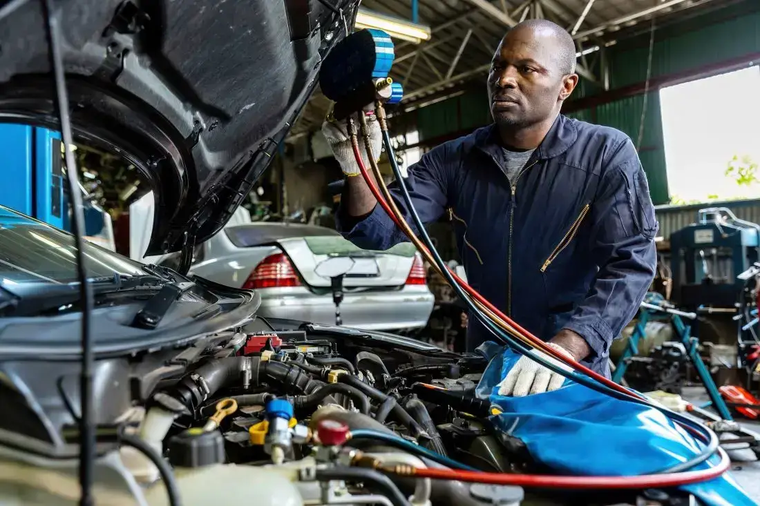 Ein Kfz-Mechaniker überprüft, ob im Auto eine CO2-Klimaanlage nachgerüstet werden kann.