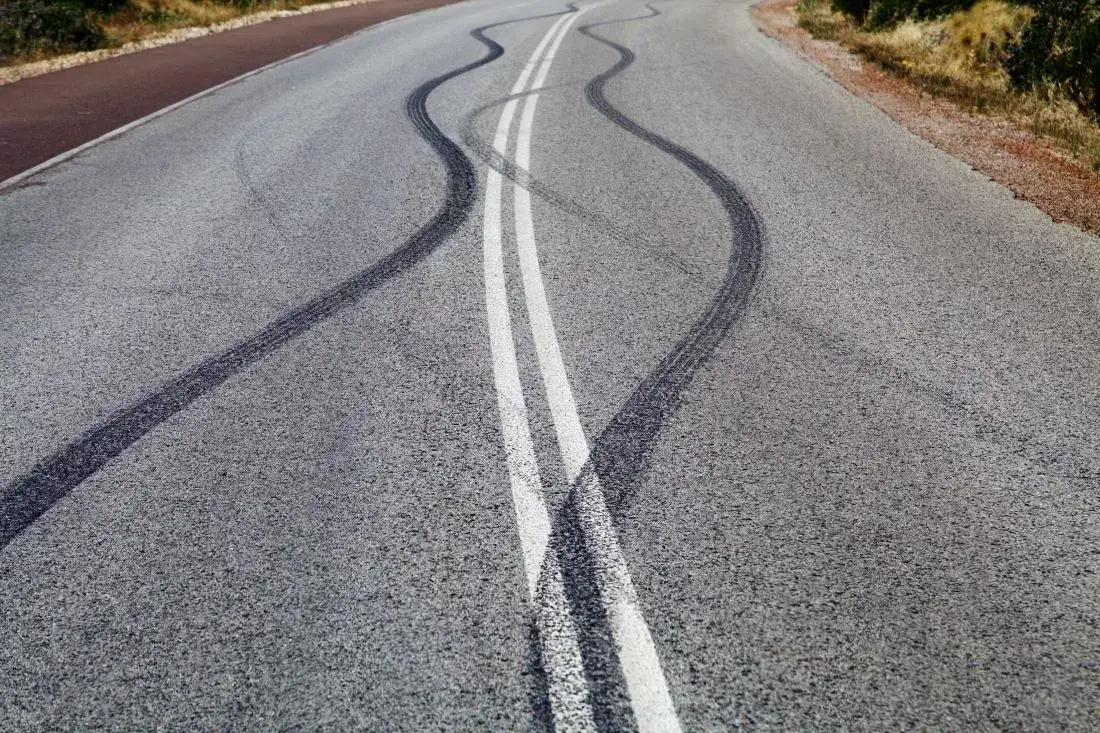 Eine unregelmäßige Reifenspur auf der Straße als Symbol für Folgen eines defekten Stoßdämpfers.