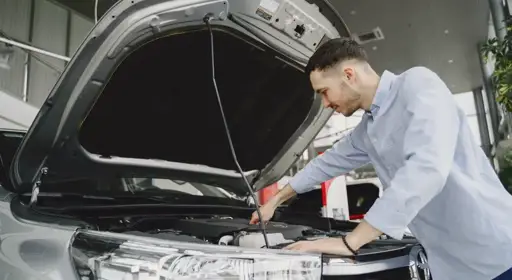 Vorbereitung Hauptuntersuchung Das Bild zeigt einen Mann, welcher Relevantes am Auto kontrolliert und sich so möglichst gut auf die HU vorbereitet.