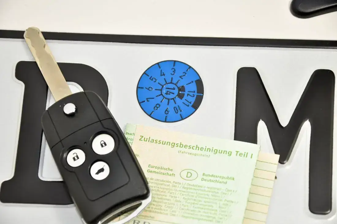 Die Grafik zeigt eine Prüfplakette, einen Autoschlüssel und einen Fahrzeugschein.