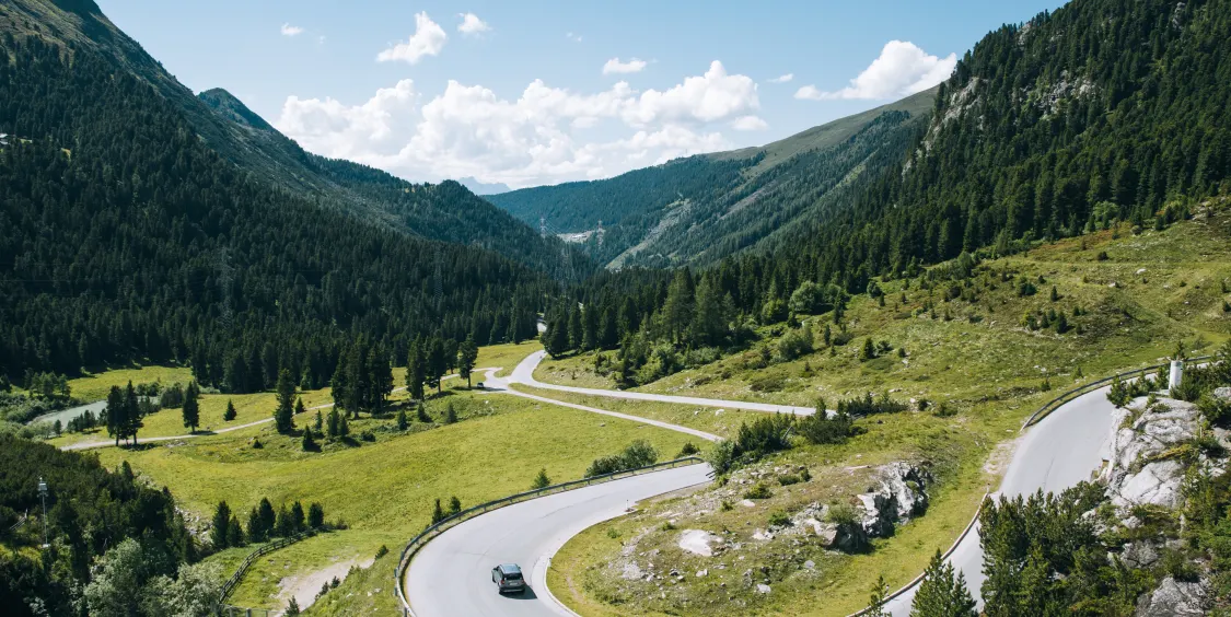 Das Bild zeigt eine kurvige Straße, bei welcher ein Auto mit guten Stoßdämpfern in der Spur bleibt und die Kontrolle beim Fahren behält.