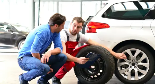 Was heißt Mischbereifung? Ein Mechaniker berät einen Mann zu einer möglichen Mischbereifung für seinen Pkw.