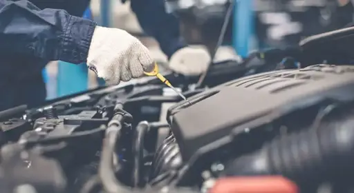 Welche Kosten fallen für einen Ölwechsel an? Die Grafik zeigt einen Mann, der den Ölstand an seinem Fahrzeug prüft und anschließend einen Ölwechsel durchführt, um Kosten zu sparen.