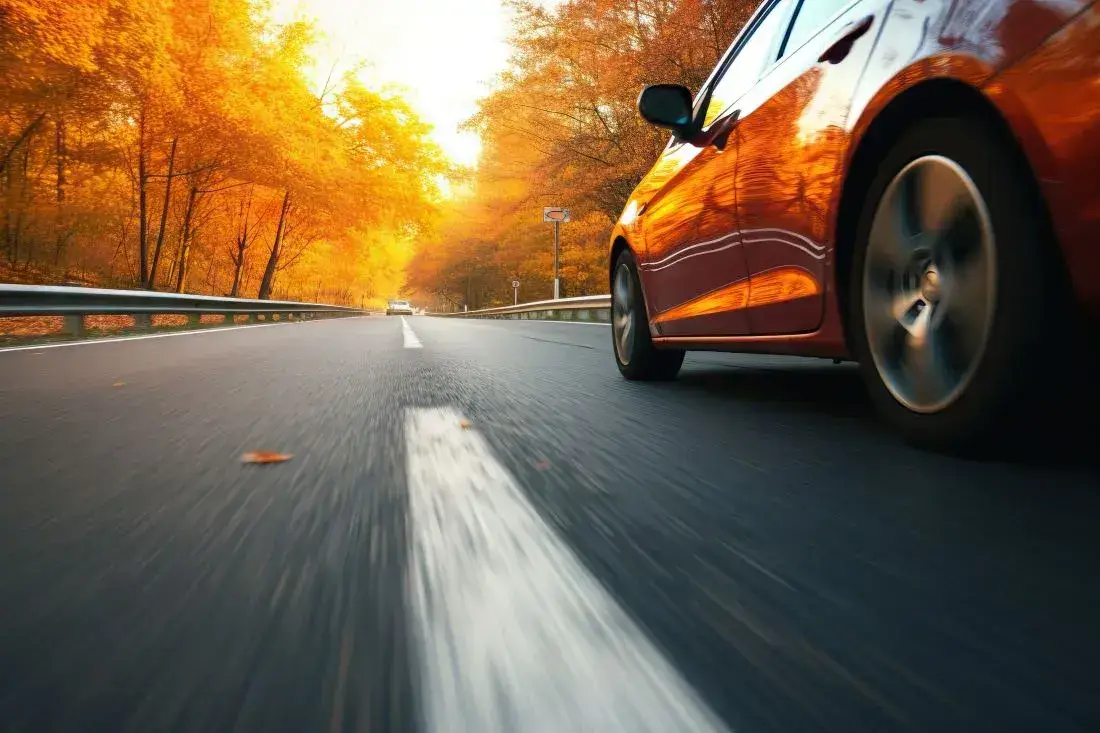 Die richtige Profiltiefe der Reifen sorgt für den passenden Grip, während ein Fahrzeug im Herbst auf nasser Fahrbahn unterwegs ist.