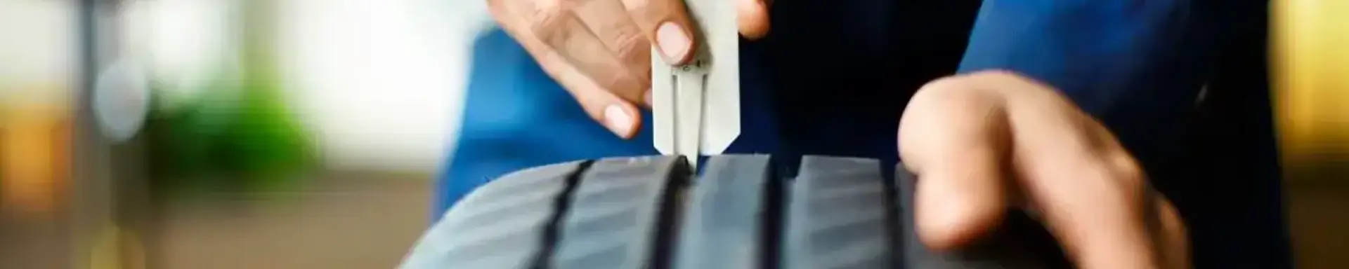 reifenprofil-messen.jpg.webp Eine Werkstattmitarbeiter misst am Reifen die Profiltiefe mit einem Profiltiefenmesser