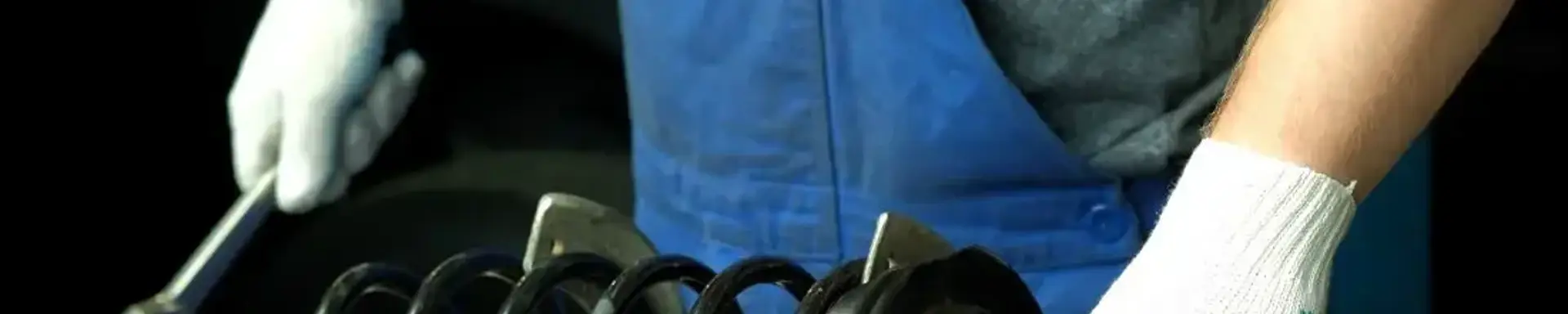 Was wird bei einer Stoßdämpfer-Reparatur gemacht? Ein Stoßdämpfer wird im Zuge einer Reparatur von einer Person inspiziert.